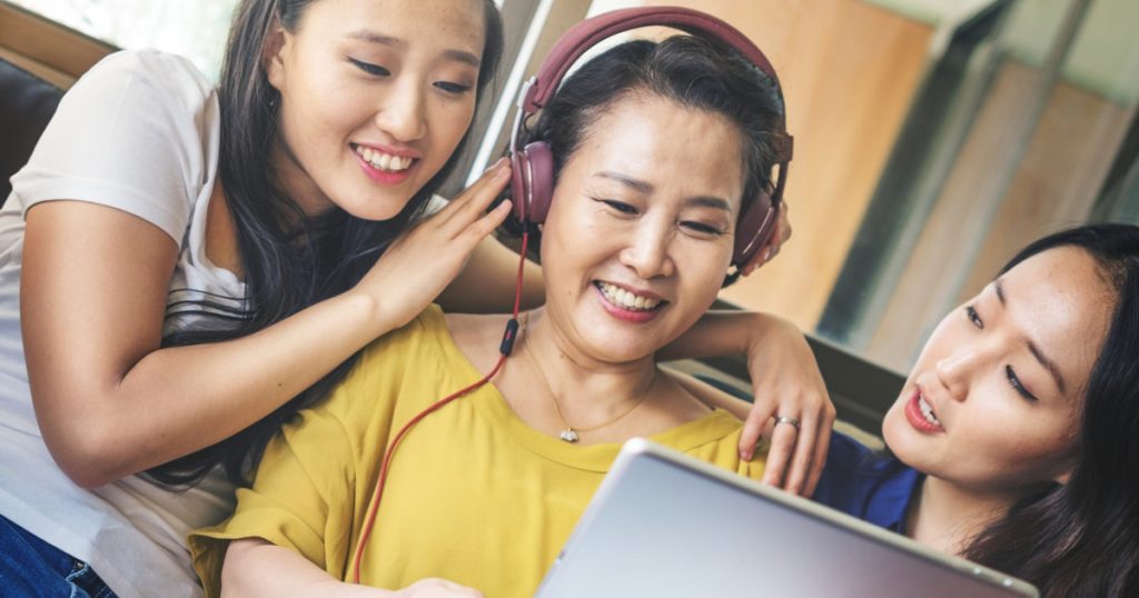 mother and daughters watching a video on a laptop